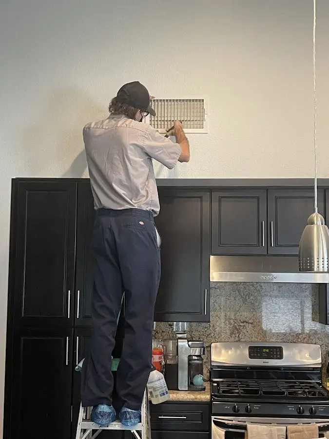 Technician inspecting an air vent during HVAC service in Four Square Mile
